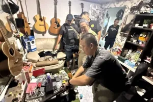 An officer with the provincial Manee Kram investigative unit inspects the house in Kathu district of Phuket where the drugs and weapons were found. (Photo: Phuket Provincial…